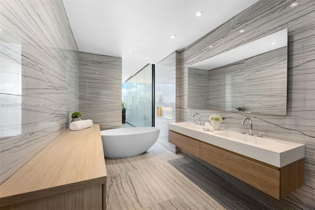 bathroom with tile walls, a tub to relax in, and vanity