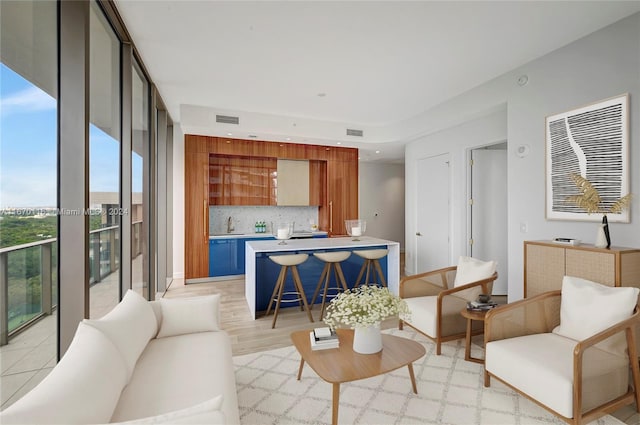 living room with wet bar, plenty of natural light, and light hardwood / wood-style flooring