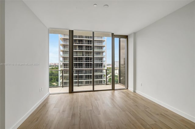 unfurnished room with expansive windows, light wood-type flooring, and a wealth of natural light