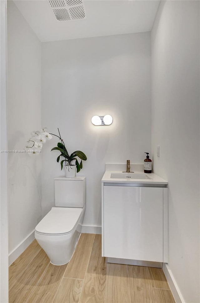 bathroom with toilet, vanity, and hardwood / wood-style flooring