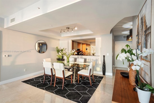 tiled dining area featuring a raised ceiling