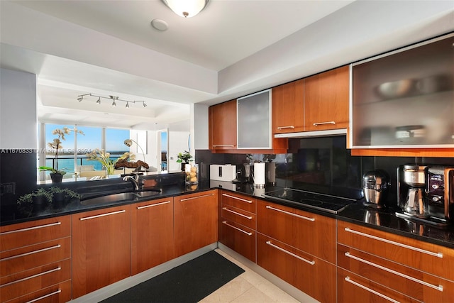 kitchen featuring dark stone countertops, backsplash, black electric stovetop, and sink