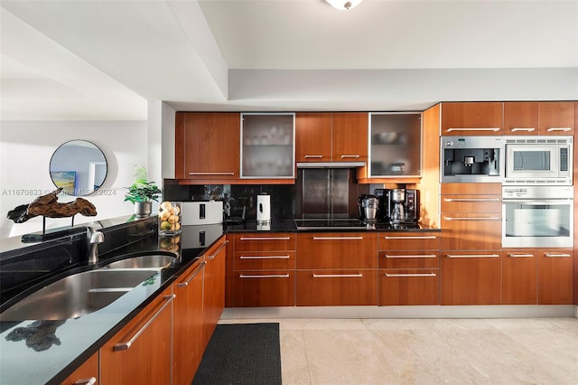 kitchen featuring light tile patterned floors, sink, dark stone countertops, black stovetop, and white microwave