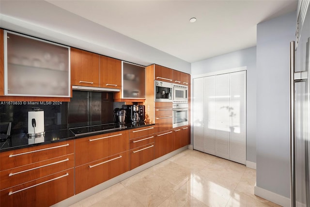 kitchen with appliances with stainless steel finishes, backsplash, dark stone countertops, and light tile patterned floors