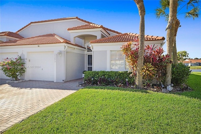 mediterranean / spanish-style house featuring a front lawn and a garage