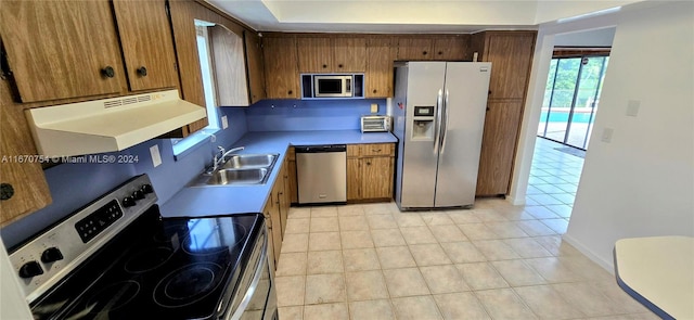 kitchen with ventilation hood, light tile patterned floors, stainless steel appliances, and sink