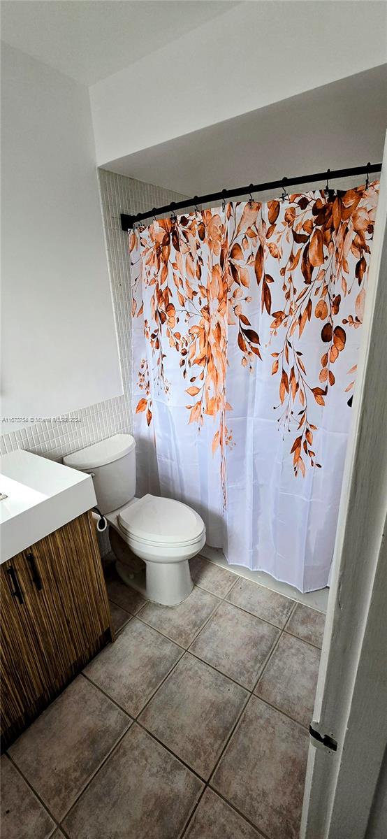 bathroom featuring a shower with shower curtain, tile patterned flooring, vanity, and toilet