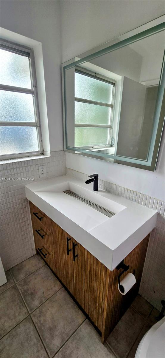 bathroom with vanity, tile walls, tile patterned flooring, and toilet