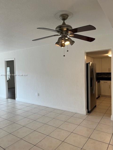 tiled empty room with ceiling fan and a textured ceiling