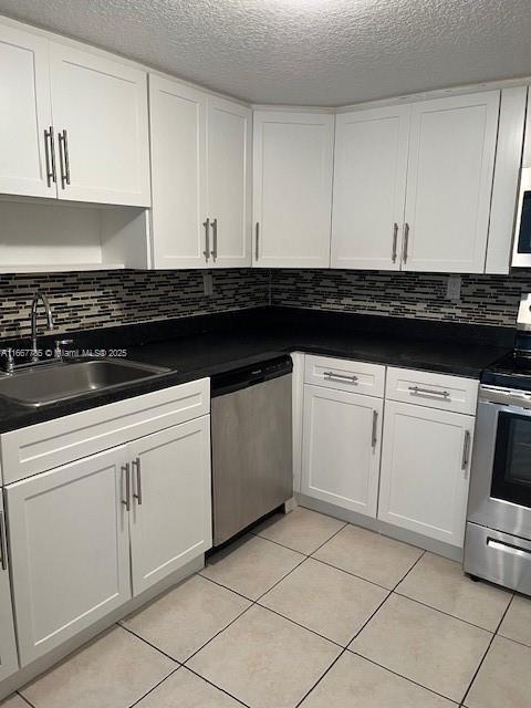 kitchen with stainless steel appliances, white cabinetry, sink, and light tile patterned flooring