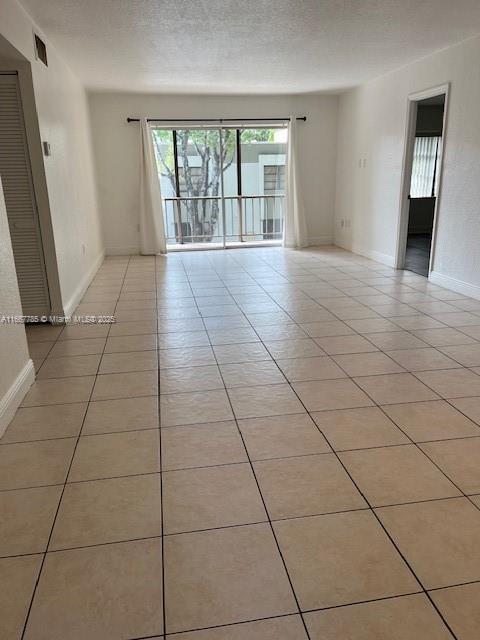 spare room with light tile patterned flooring and a textured ceiling