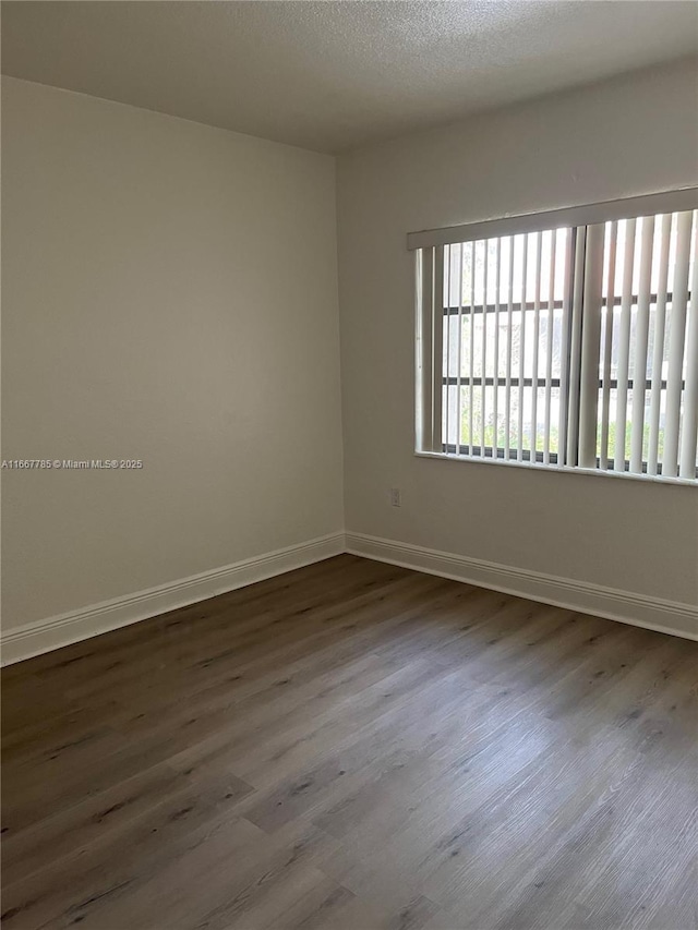 spare room featuring wood-type flooring and a textured ceiling