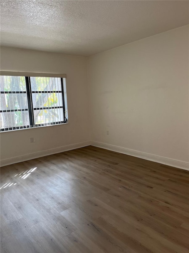 empty room with dark wood-type flooring and a textured ceiling