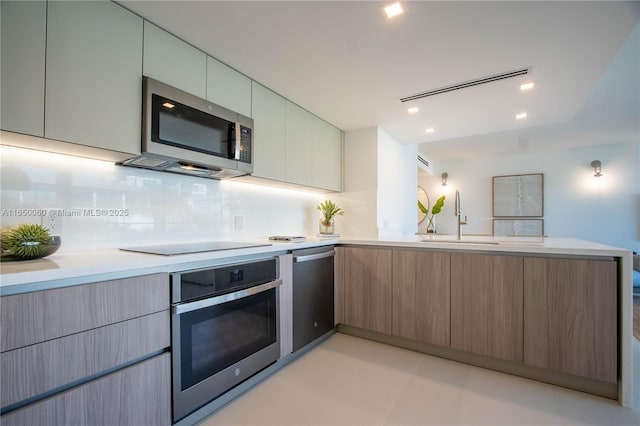 kitchen featuring sink, decorative backsplash, kitchen peninsula, and stainless steel appliances