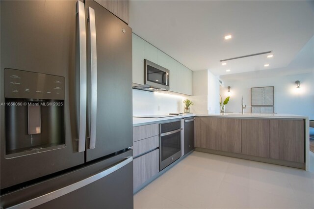 150 Sunrise Dr Unit 4B, Key Biscayne, FL 33149 - kitchen featuring appliances with stainless steel finishes, modern cabinets, light countertops, and a peninsula