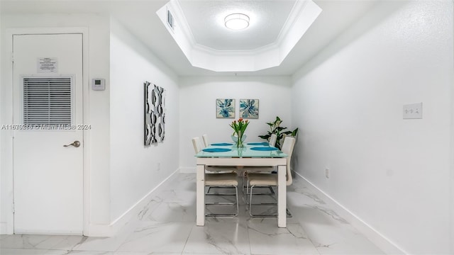 dining room with a textured ceiling, a tray ceiling, and ornamental molding