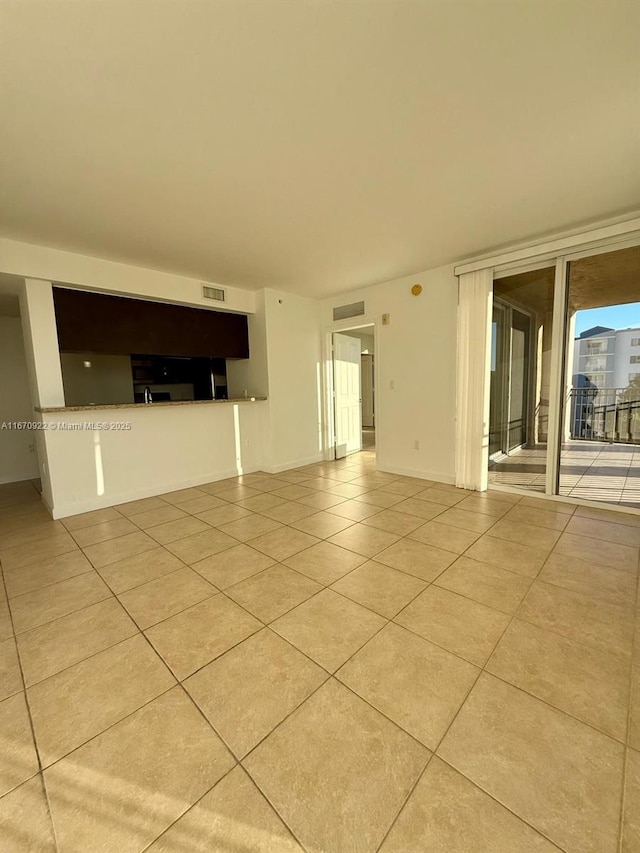 empty room featuring visible vents, baseboards, and light tile patterned floors