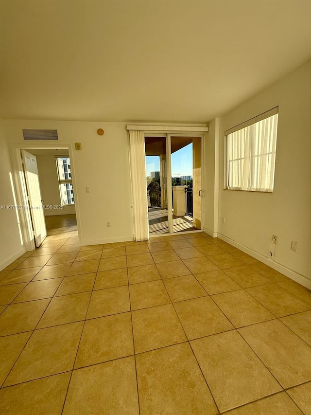 tiled spare room with plenty of natural light and baseboards