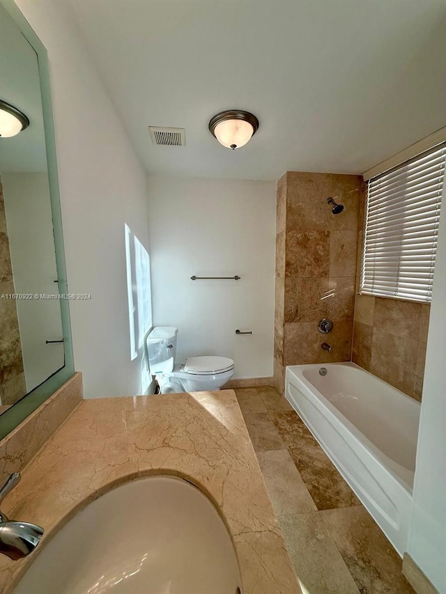 full bathroom featuring vanity, tiled shower / bath combo, and toilet