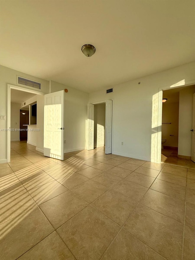 spare room featuring light tile patterned flooring and visible vents