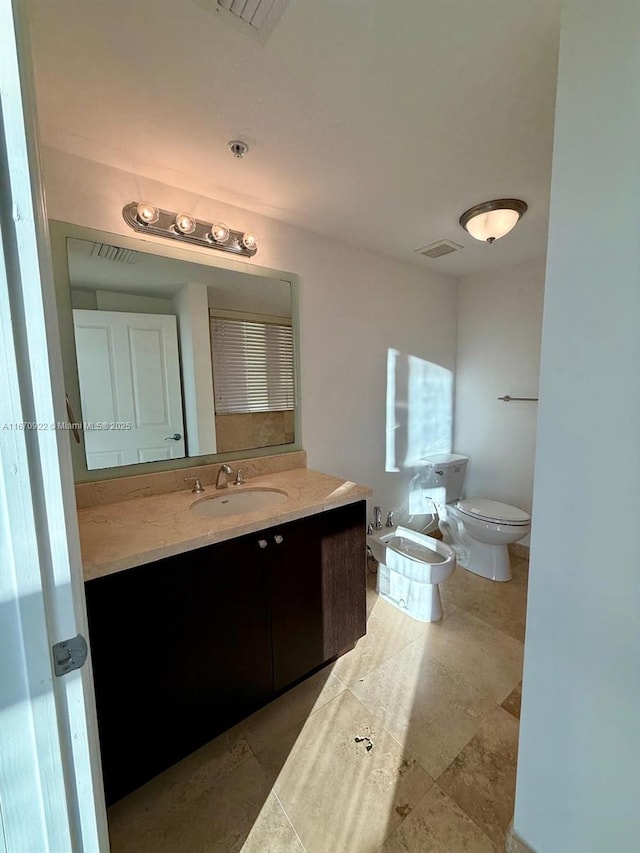 bathroom with visible vents, a bidet, vanity, and toilet