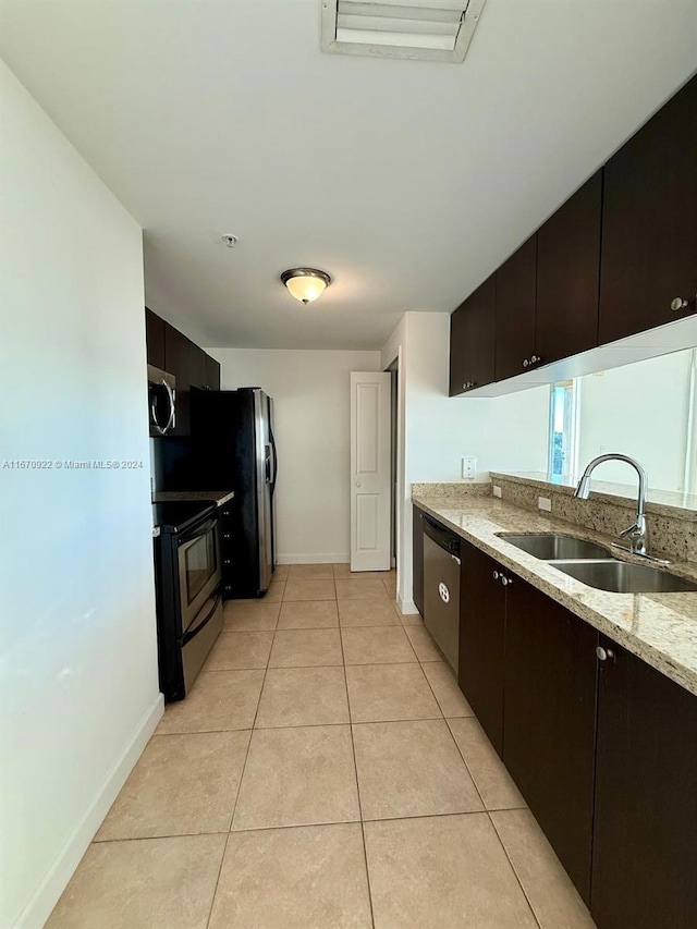 kitchen with dark brown cabinetry, light stone countertops, sink, light tile patterned floors, and appliances with stainless steel finishes