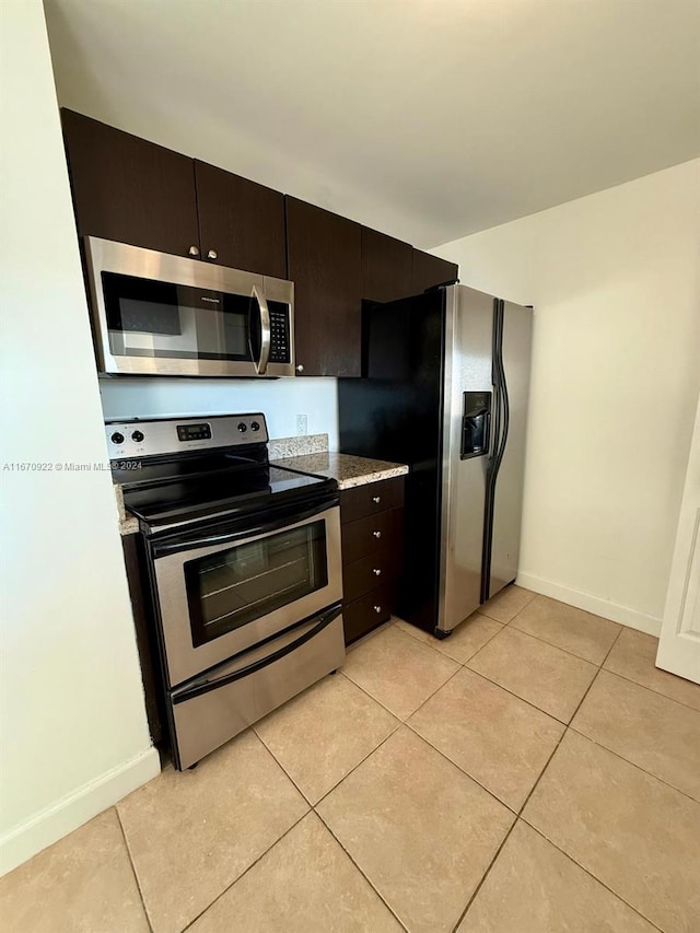 kitchen featuring dark brown cabinetry, light tile patterned flooring, and stainless steel appliances