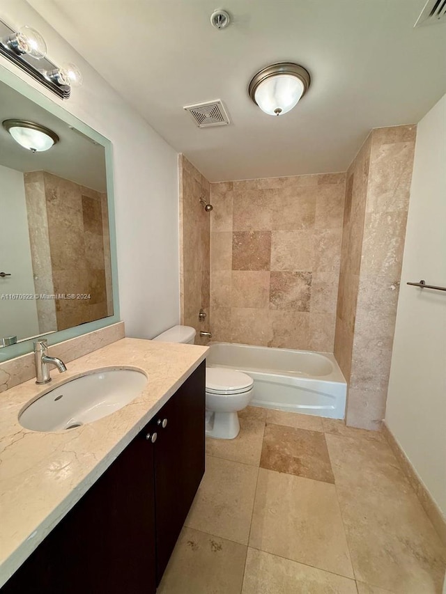 full bathroom featuring tile patterned floors, vanity, tiled shower / bath, and toilet