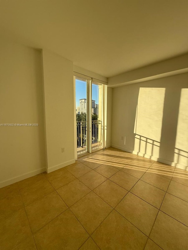 empty room with baseboards, a city view, and tile patterned floors