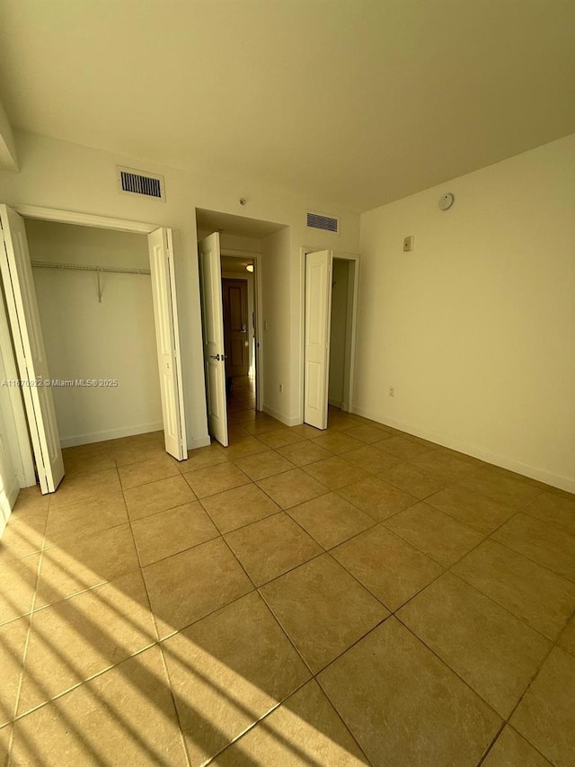 unfurnished bedroom with visible vents, baseboards, and light tile patterned floors