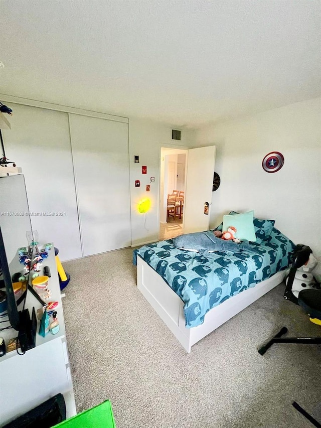 carpeted bedroom with a textured ceiling and a closet