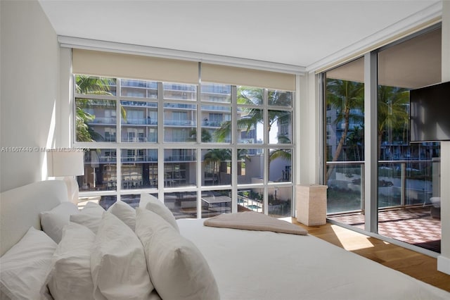 bedroom featuring wood-type flooring, multiple windows, and a wall of windows