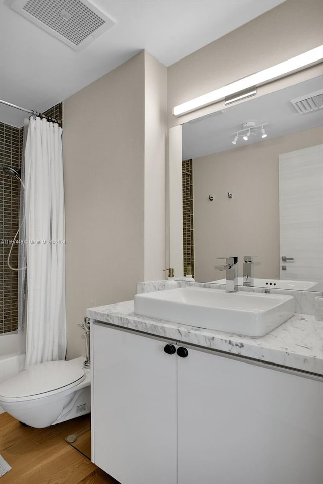 full bathroom featuring vanity, hardwood / wood-style flooring, toilet, and shower / tub combo