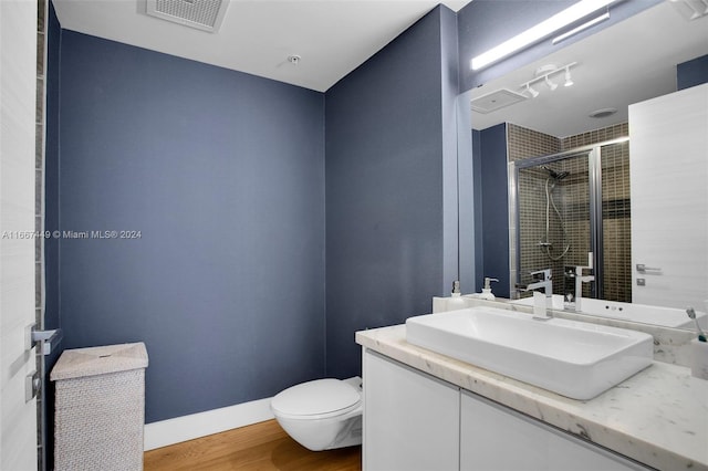 bathroom featuring toilet, vanity, wood-type flooring, and walk in shower