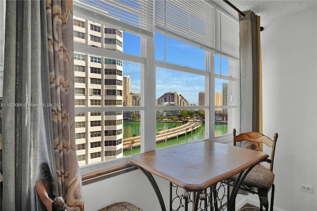 dining space featuring a textured ceiling, a water view, and a wealth of natural light