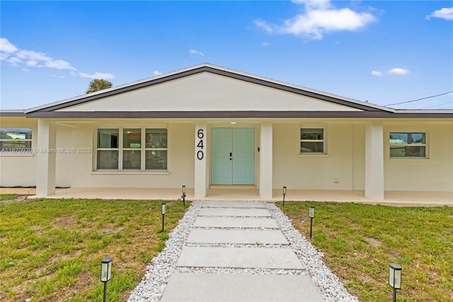 view of front of home featuring a porch, stucco siding, and a front lawn