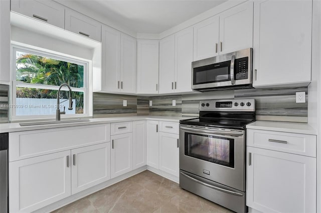 kitchen with white cabinetry, light countertops, backsplash, stainless steel appliances, and a sink