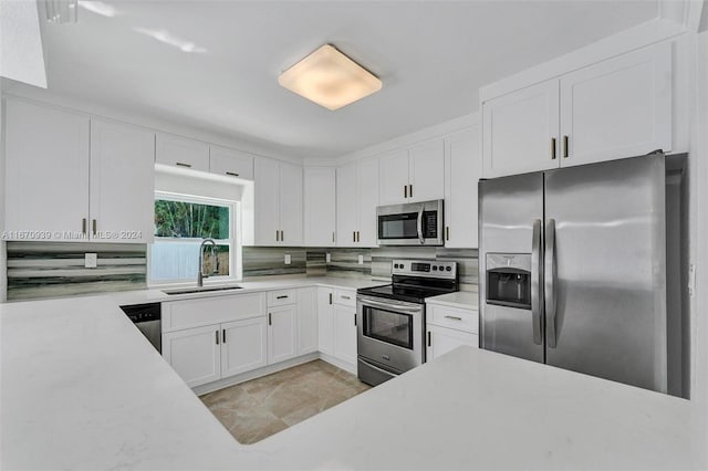 kitchen featuring tasteful backsplash, white cabinetry, appliances with stainless steel finishes, and sink