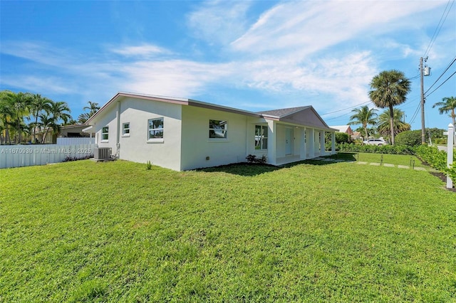 rear view of house featuring stucco siding, cooling unit, fence, and a lawn