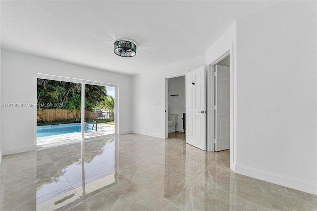 unfurnished room featuring marble finish floor and baseboards