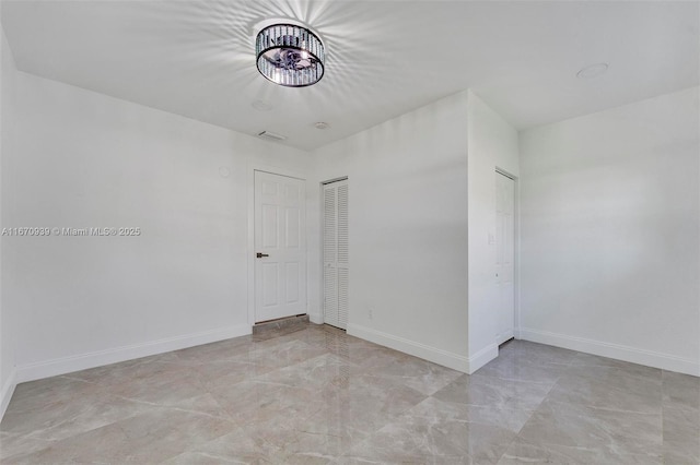 spare room with baseboards, visible vents, marble finish floor, and an inviting chandelier