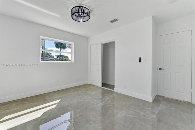 unfurnished bedroom with a closet, marble finish floor, visible vents, and baseboards