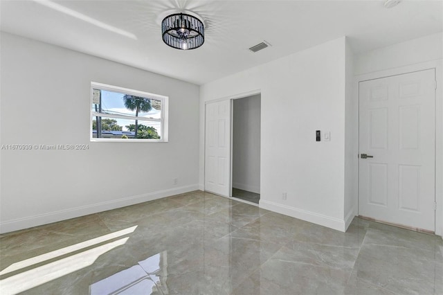 unfurnished bedroom with an inviting chandelier