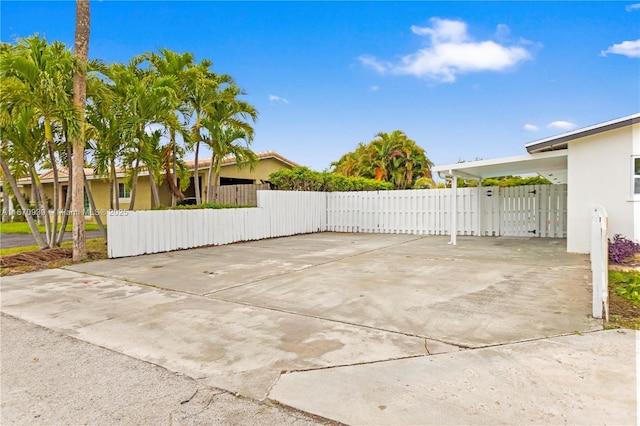 view of patio featuring concrete driveway, fence, and a gate