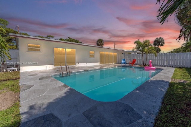 pool at dusk featuring a patio