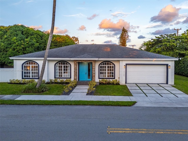 ranch-style home with a garage and a lawn