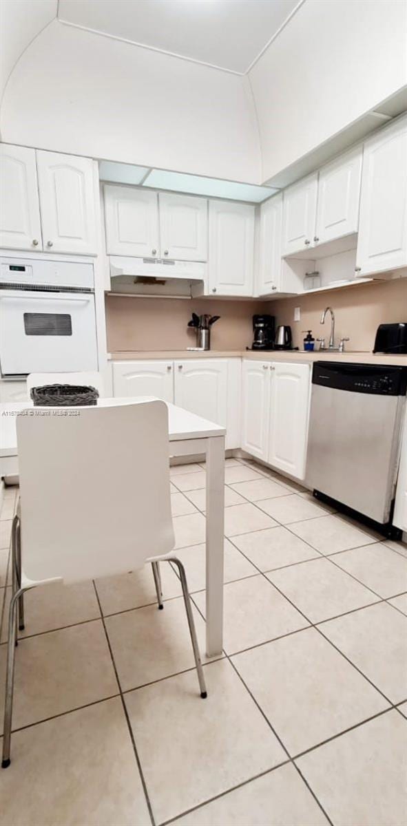 19370 Collins Ave Unit 207, Sunny Isles Beach, FL 33160 - kitchen with stainless steel dishwasher, oven, under cabinet range hood, light countertops, and light tile patterned flooring