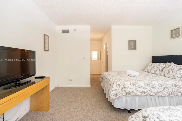 bedroom featuring a textured ceiling and light colored carpet