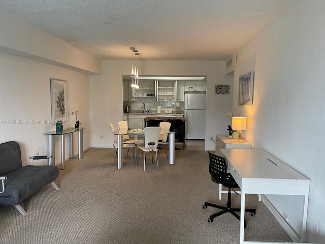 dining space featuring a textured ceiling, carpet floors, and sink