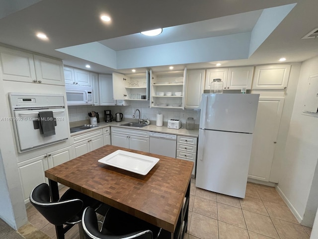 kitchen featuring backsplash, sink, white appliances, and white cabinetry